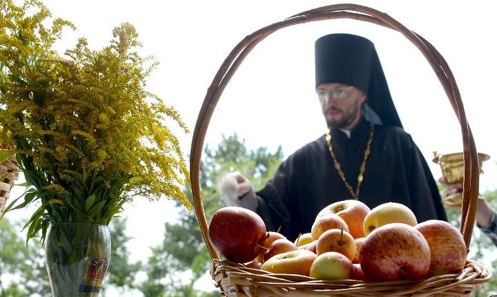 корзина з яблуками і букет мімози на тлі священика