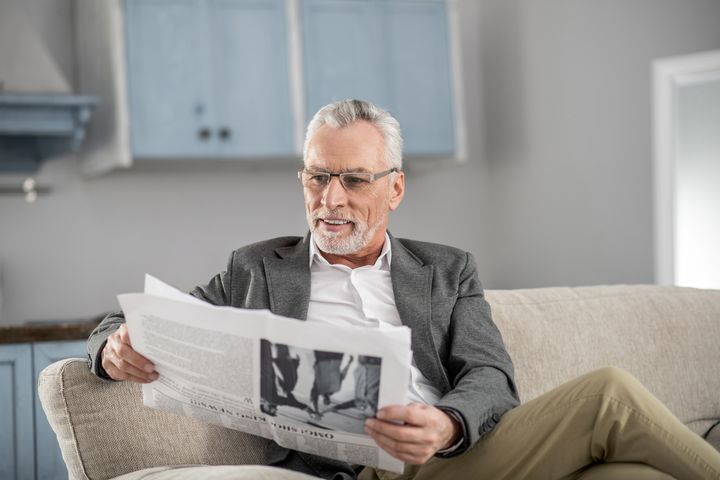 Чоловік передпенсійного віку читає газету