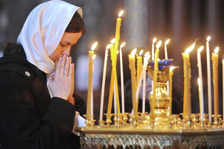 дівчина ставить свічку і молиться