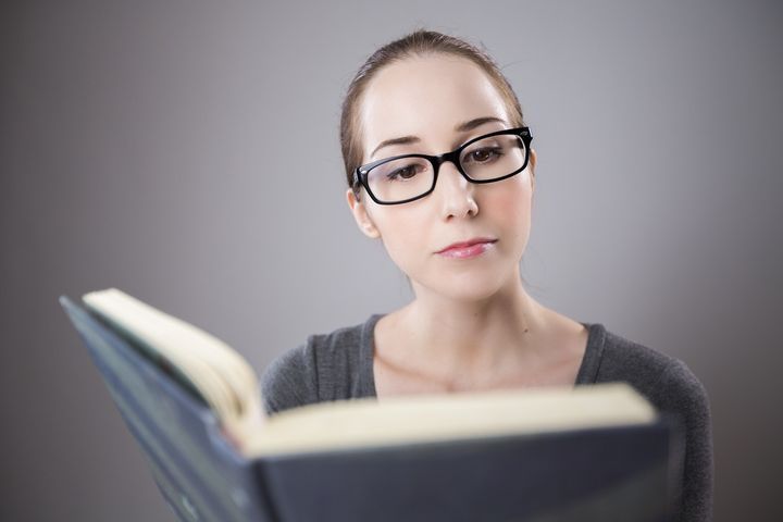 Дівчина в окулярах читає книгу