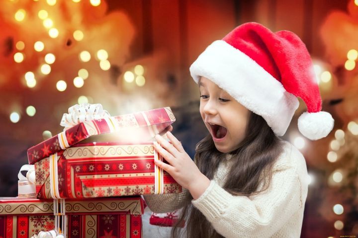 Дівчинка відкриває новорічний подарунок